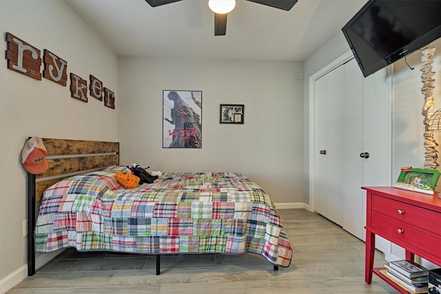 bedroom with a closet, wood finished floors, a ceiling fan, and baseboards