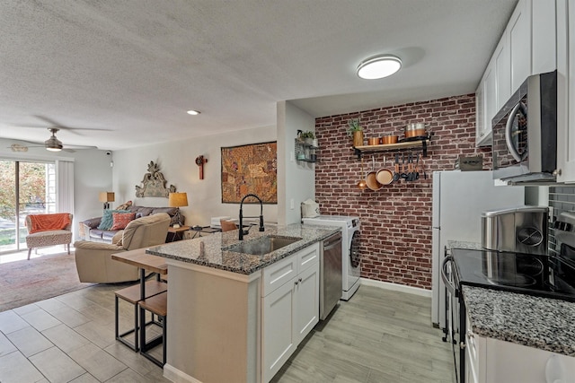 kitchen with stainless steel appliances, a breakfast bar, a peninsula, a sink, and white cabinetry