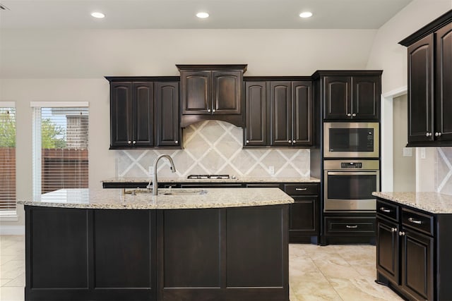 5615 Alexan Crest Dr, Fulshear, TX 77441 - kitchen featuring stainless steel appliances, a center island with sink, a sink, light stone counters, and recessed lighting