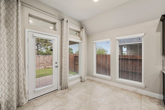 doorway with lofted ceiling, light tile patterned floors, and baseboards