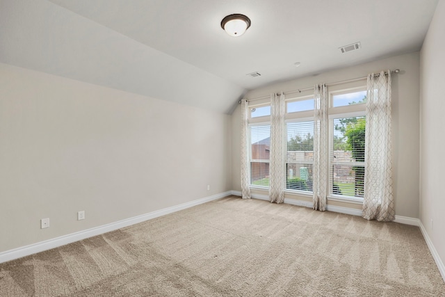 carpeted empty room with lofted ceiling, visible vents, and baseboards