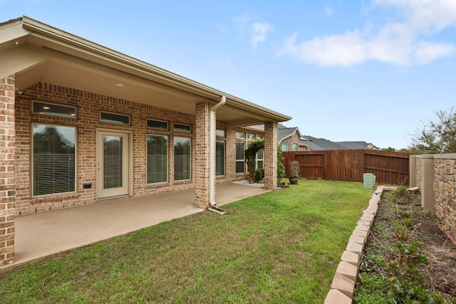 rear view of property with brick siding, a lawn, a patio area, and a fenced backyard