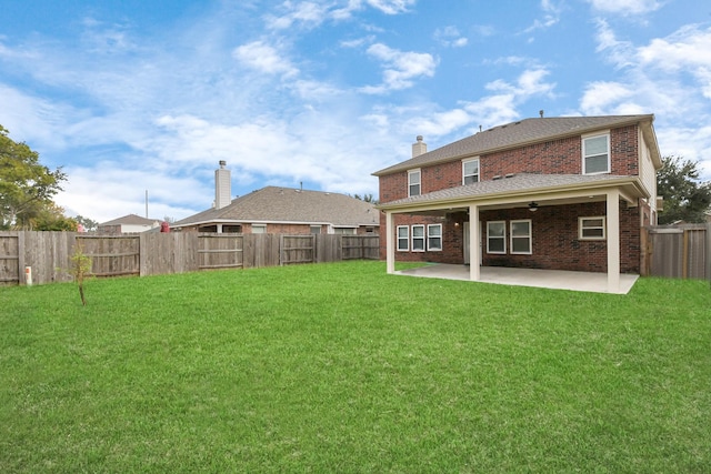 rear view of property with brick siding, a lawn, and a patio