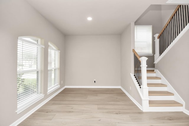 empty room featuring recessed lighting, stairway, light wood-type flooring, and baseboards