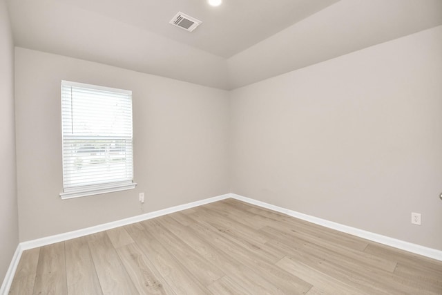 empty room with visible vents, light wood-style flooring, and baseboards