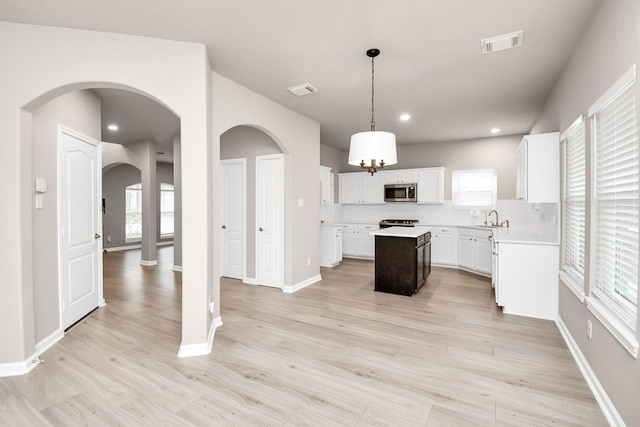 kitchen featuring a kitchen island, visible vents, light wood-style floors, light countertops, and stainless steel microwave