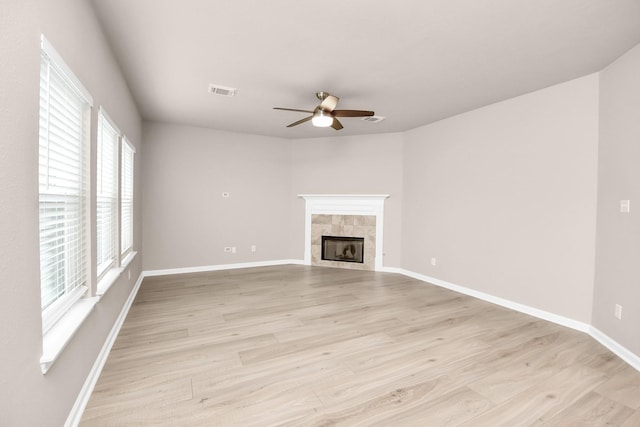 unfurnished living room featuring a fireplace, visible vents, light wood-style flooring, ceiling fan, and baseboards