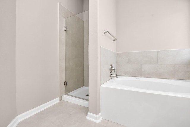 bathroom with tile patterned flooring, a garden tub, a shower stall, and baseboards