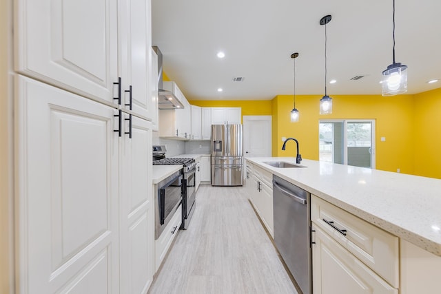 kitchen featuring pendant lighting, stainless steel appliances, a sink, and white cabinets