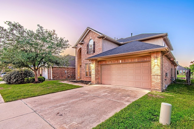 traditional home featuring brick siding, an attached garage, fence, driveway, and a front lawn