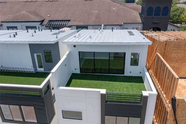 back of house with fence private yard, a standing seam roof, a yard, and metal roof