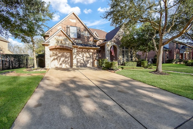 view of front facade with driveway, a front lawn, stone siding, fence, and brick siding