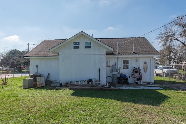 rear view of property featuring roof with shingles, a lawn, fence, and central air condition unit