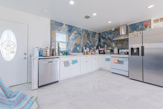 kitchen featuring stainless steel appliances, light countertops, visible vents, white cabinets, and wall chimney exhaust hood