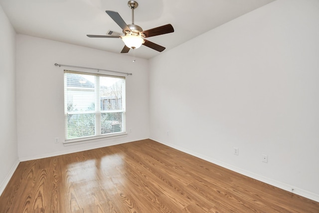 spare room featuring ceiling fan, baseboards, and wood finished floors