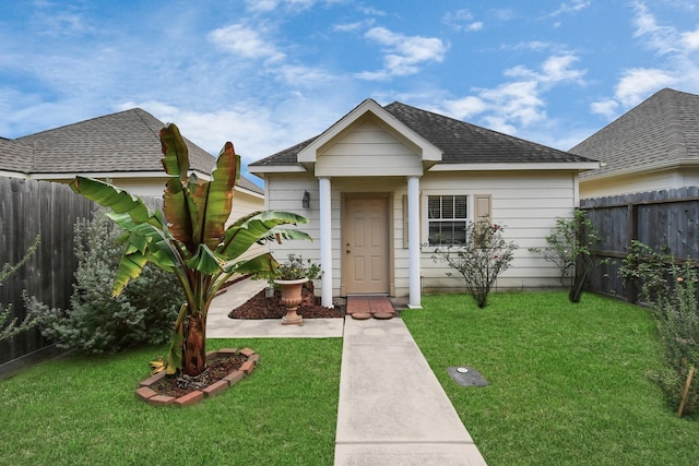 bungalow-style home featuring a front lawn, a shingled roof, and fence