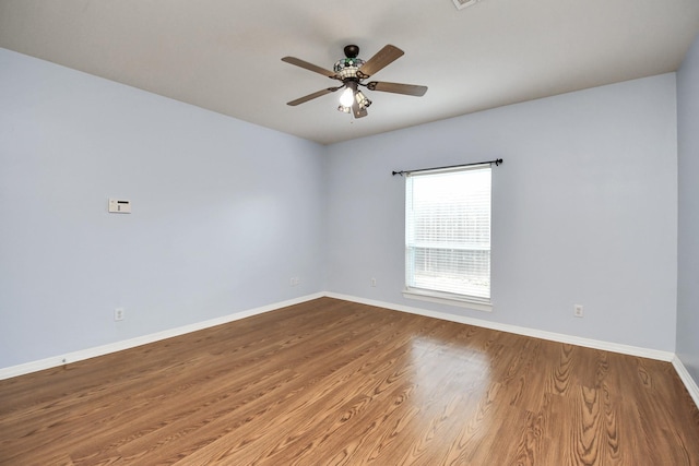 empty room featuring ceiling fan, wood finished floors, visible vents, and baseboards