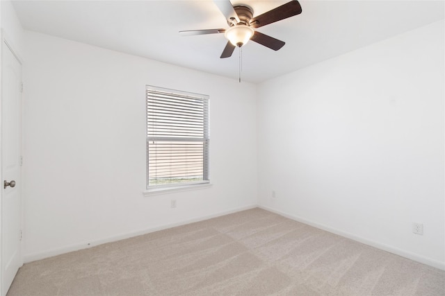 spare room with light carpet, ceiling fan, and baseboards