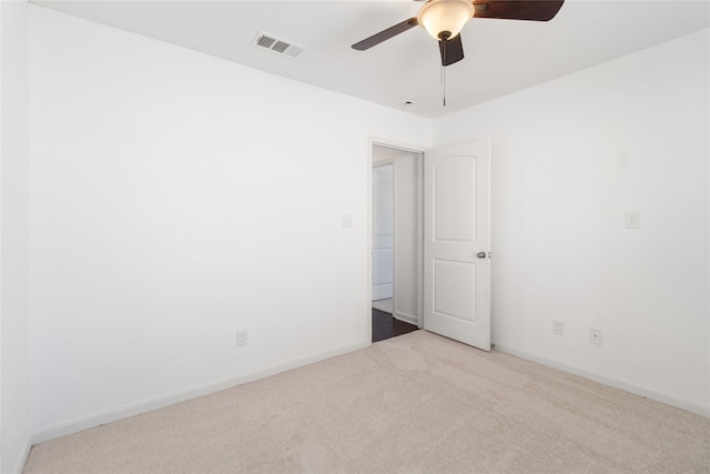 carpeted empty room featuring baseboards, visible vents, and ceiling fan