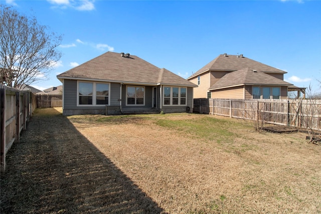 rear view of house featuring a fenced backyard and a yard