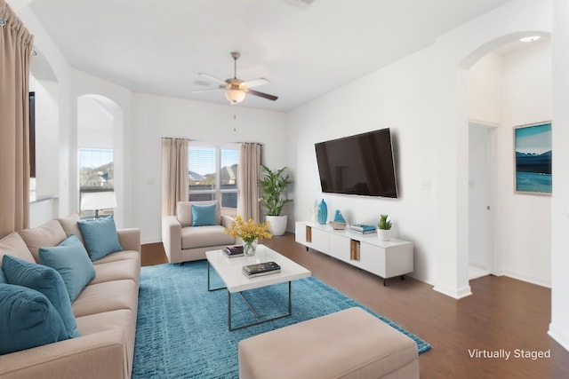 living room with arched walkways, wood finished floors, a ceiling fan, and baseboards