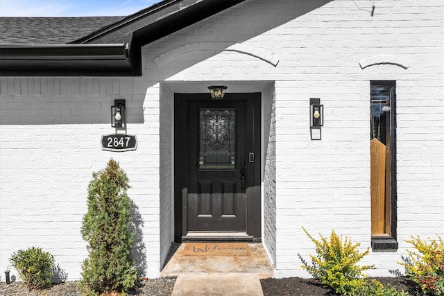 property entrance with brick siding and a shingled roof