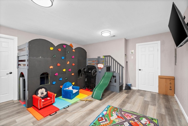 recreation room with visible vents, baseboards, and wood finished floors