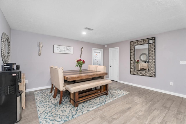 dining room with visible vents, a textured ceiling, baseboards, and wood finished floors