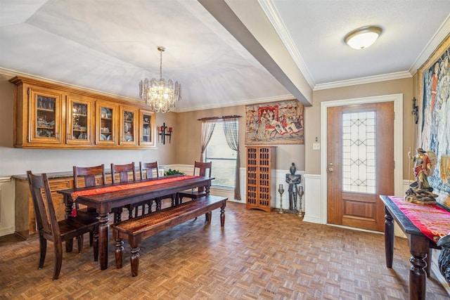 dining room with crown molding, a wainscoted wall, a notable chandelier, and a textured ceiling