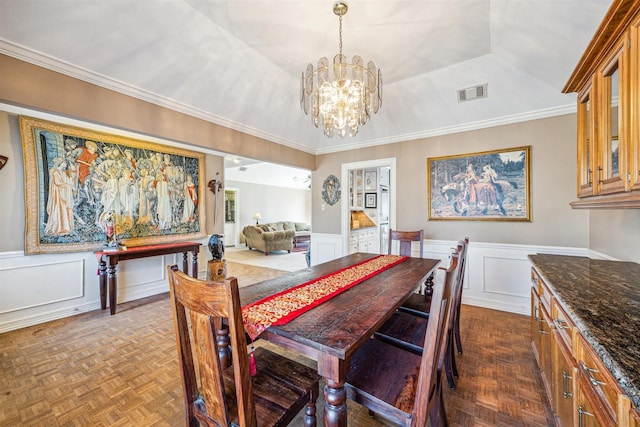 dining room featuring visible vents, a raised ceiling, wainscoting, ornamental molding, and a notable chandelier