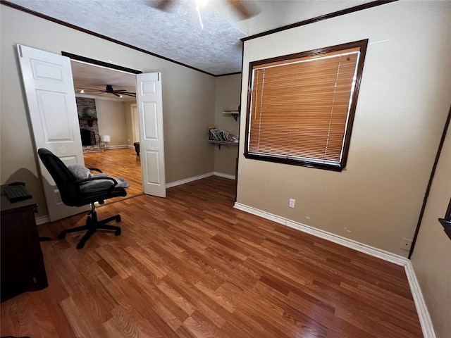 office featuring a textured ceiling, a ceiling fan, crown molding, and wood finished floors