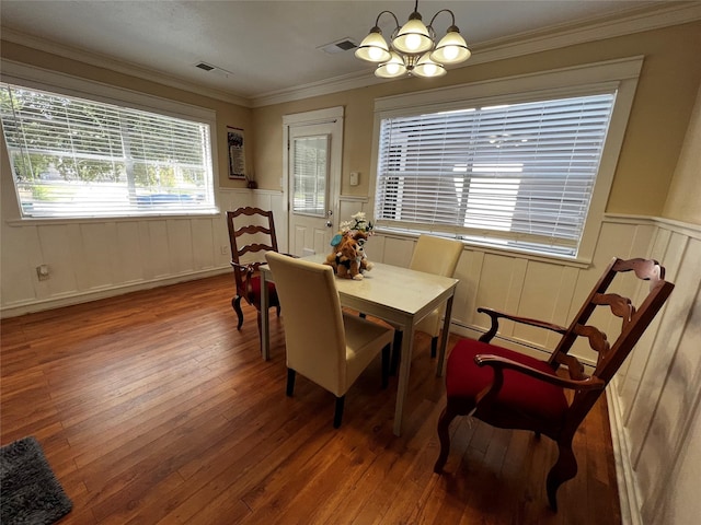 dining area featuring a wainscoted wall, ornamental molding, wood-type flooring, and visible vents