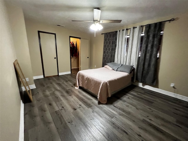 bedroom featuring visible vents, a spacious closet, baseboards, and wood finished floors