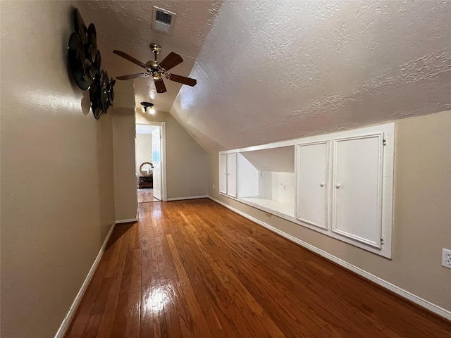 bonus room featuring visible vents, hardwood / wood-style floors, vaulted ceiling, a textured ceiling, and baseboards