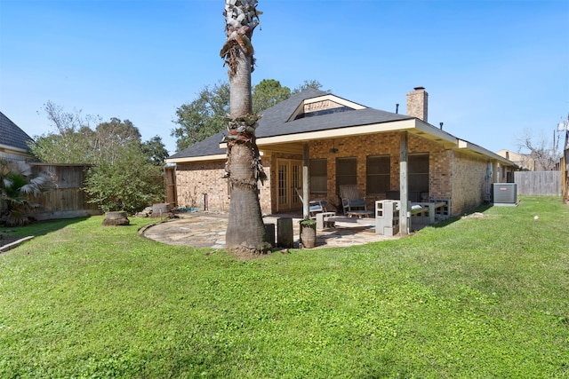 back of property with a fenced backyard, central AC, brick siding, a yard, and a patio area