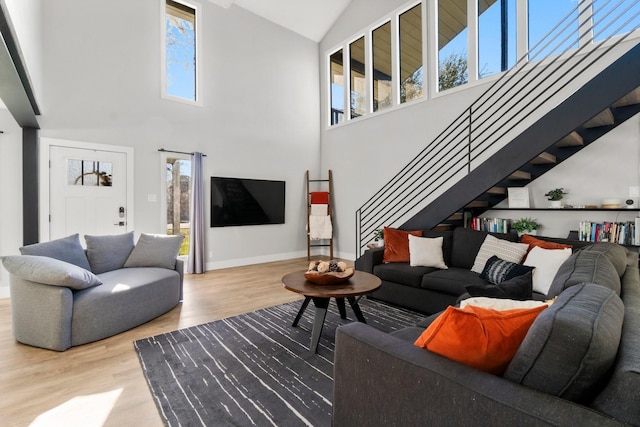 living area featuring baseboards, stairway, vaulted ceiling, and wood finished floors