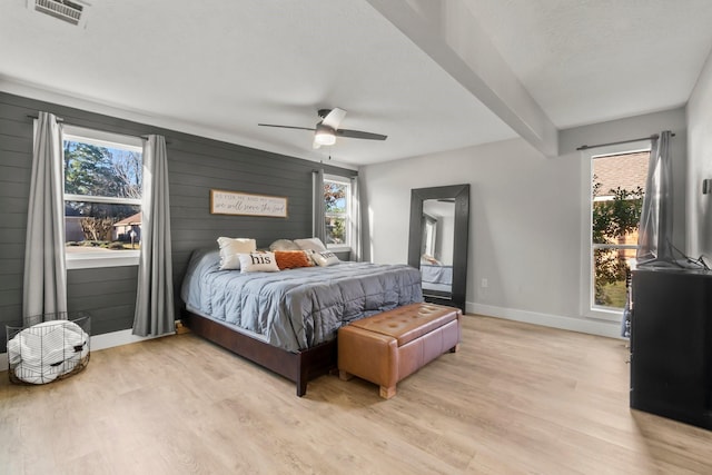 bedroom featuring baseboards, visible vents, wooden walls, and light wood finished floors