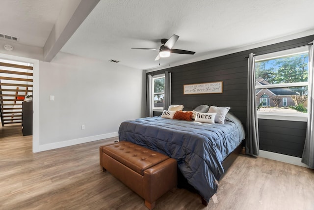 bedroom featuring a textured ceiling, wood finished floors, visible vents, and baseboards