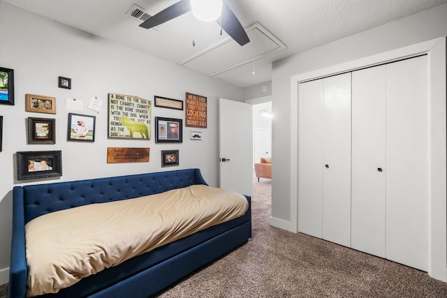 carpeted bedroom with a ceiling fan, attic access, visible vents, and a closet