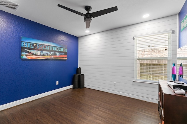 interior space featuring baseboards, visible vents, a ceiling fan, a textured wall, and wood finished floors