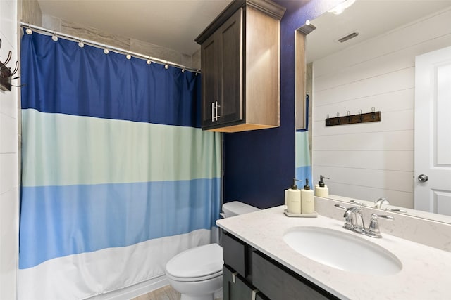 bathroom featuring visible vents, a shower with shower curtain, toilet, wooden walls, and vanity