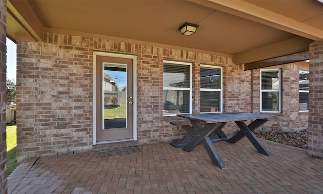 doorway to property featuring a patio and brick siding