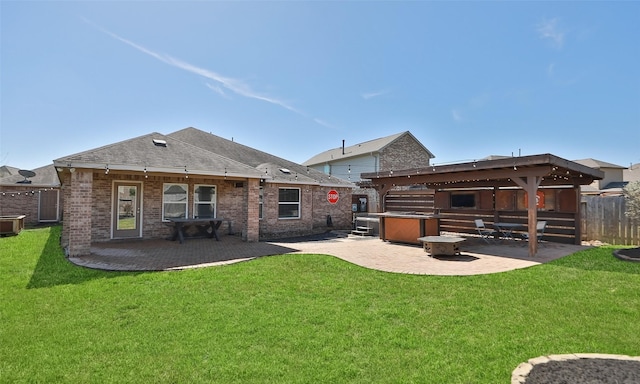 back of property with a yard, brick siding, a patio area, and fence