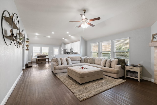 living area with vaulted ceiling, dark wood-type flooring, a ceiling fan, and baseboards