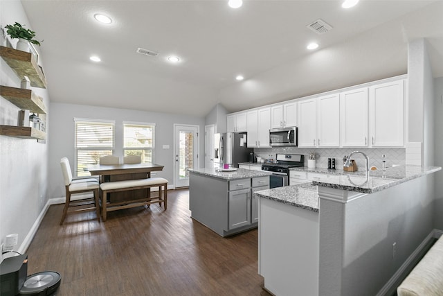 kitchen with lofted ceiling, visible vents, stainless steel appliances, and a center island