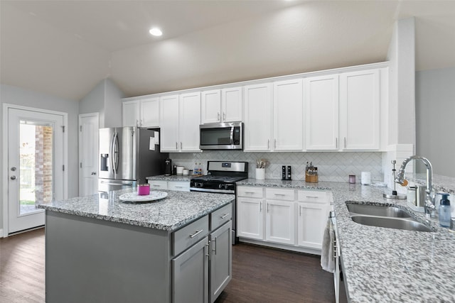 kitchen with lofted ceiling, white cabinetry, stainless steel appliances, and a sink