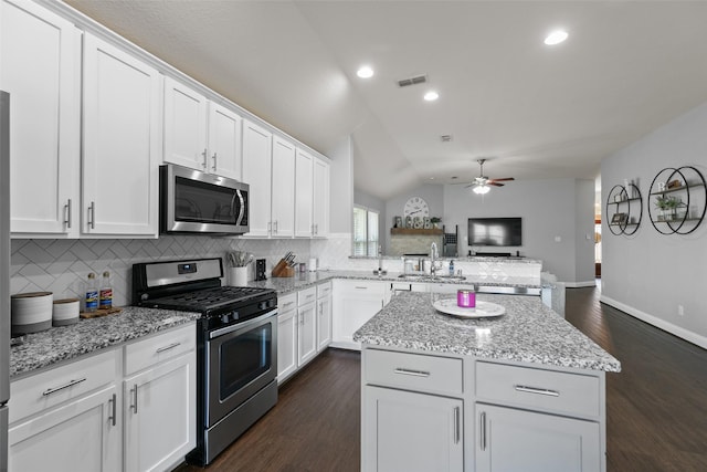 kitchen with stainless steel appliances, visible vents, decorative backsplash, vaulted ceiling, and a peninsula