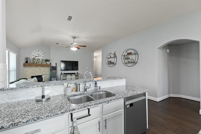 kitchen featuring visible vents, a sink, a stone fireplace, and light stone countertops