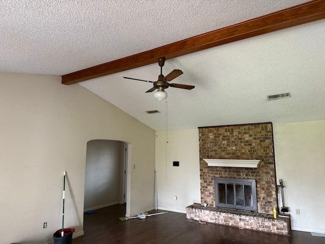 unfurnished living room with lofted ceiling with beams, a brick fireplace, visible vents, and wood finished floors