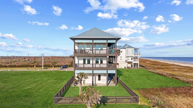 back of property featuring a balcony, a water view, a fenced backyard, and a yard